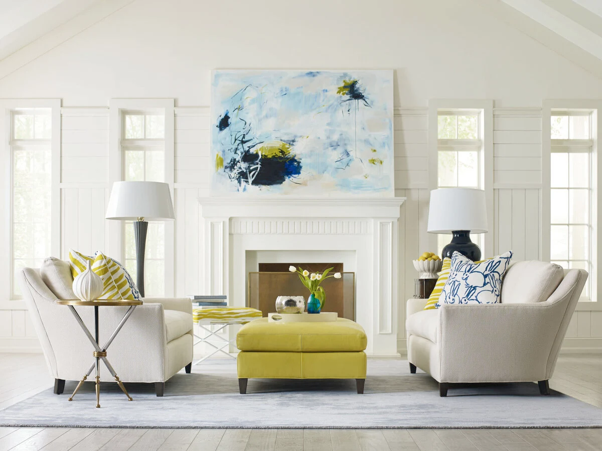 White living room chairs with a chartreuse ottoman in front of a fireplace