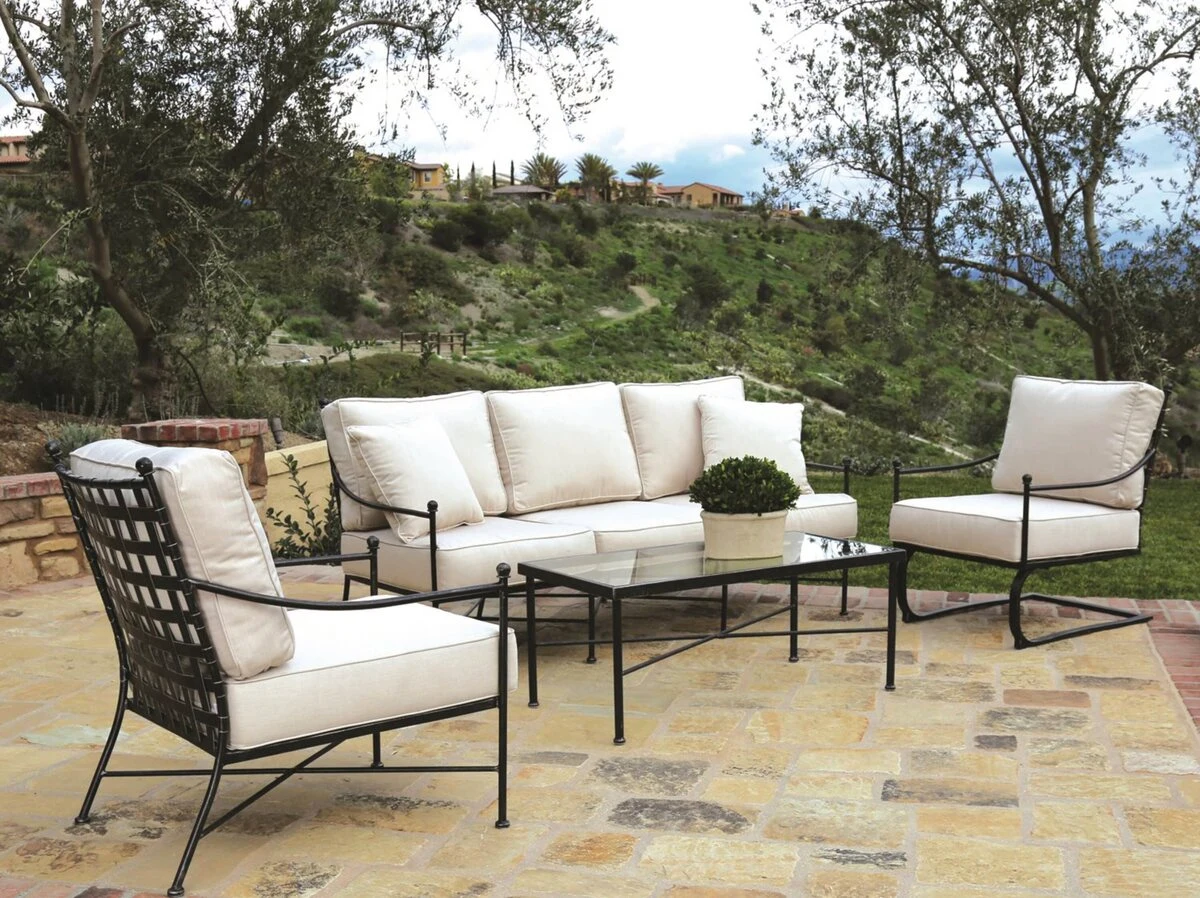 Outdoor sofa and lounge chairs with cream cushions on a stone patio