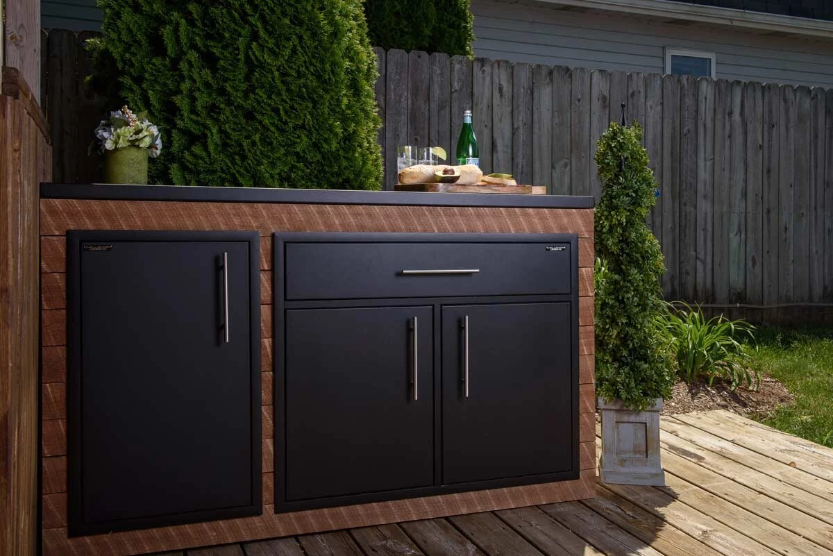 Custom outdoor kitchen with dark aluminum cabinetry and stainless steel pulls in a contemporary outdoor setting.