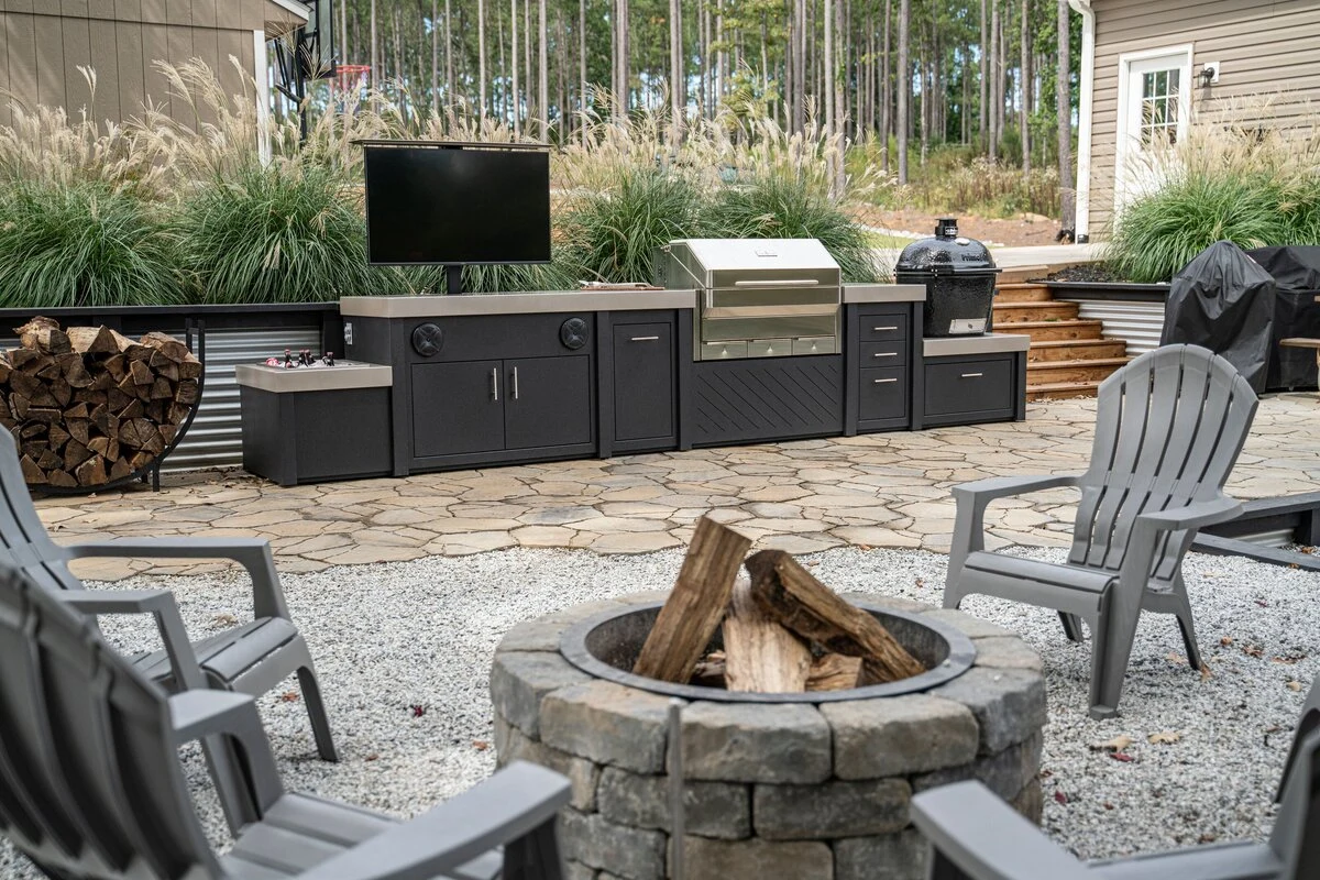 Custom outdoor kitchen with fire pit and mixed seating on a warm stone patio. Available near Hayden, Rathdrum, and Spokane.