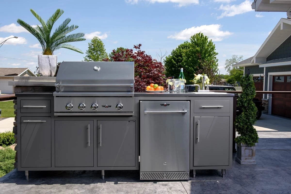 Custom outdoor kitchen with stainless steel grill and cabinetry on a bright open patio with greenery. Shop outdoor kitchens near Spokane, ID.
