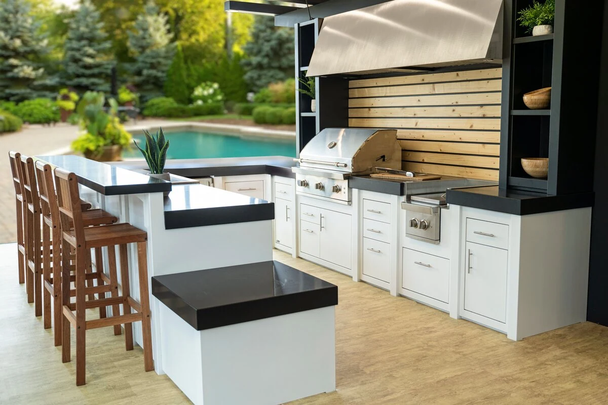 Custom outdoor kitchen with black granite countertops and stainless steel grill on a modern patio. Visit our Post Falls showroom.
