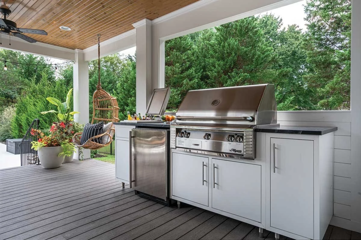 Custom outdoor kitchen with white cabinetry, stainless steel grill, and pergola on a covered patio. Shop near Post Falls and Coeur d'Alene.