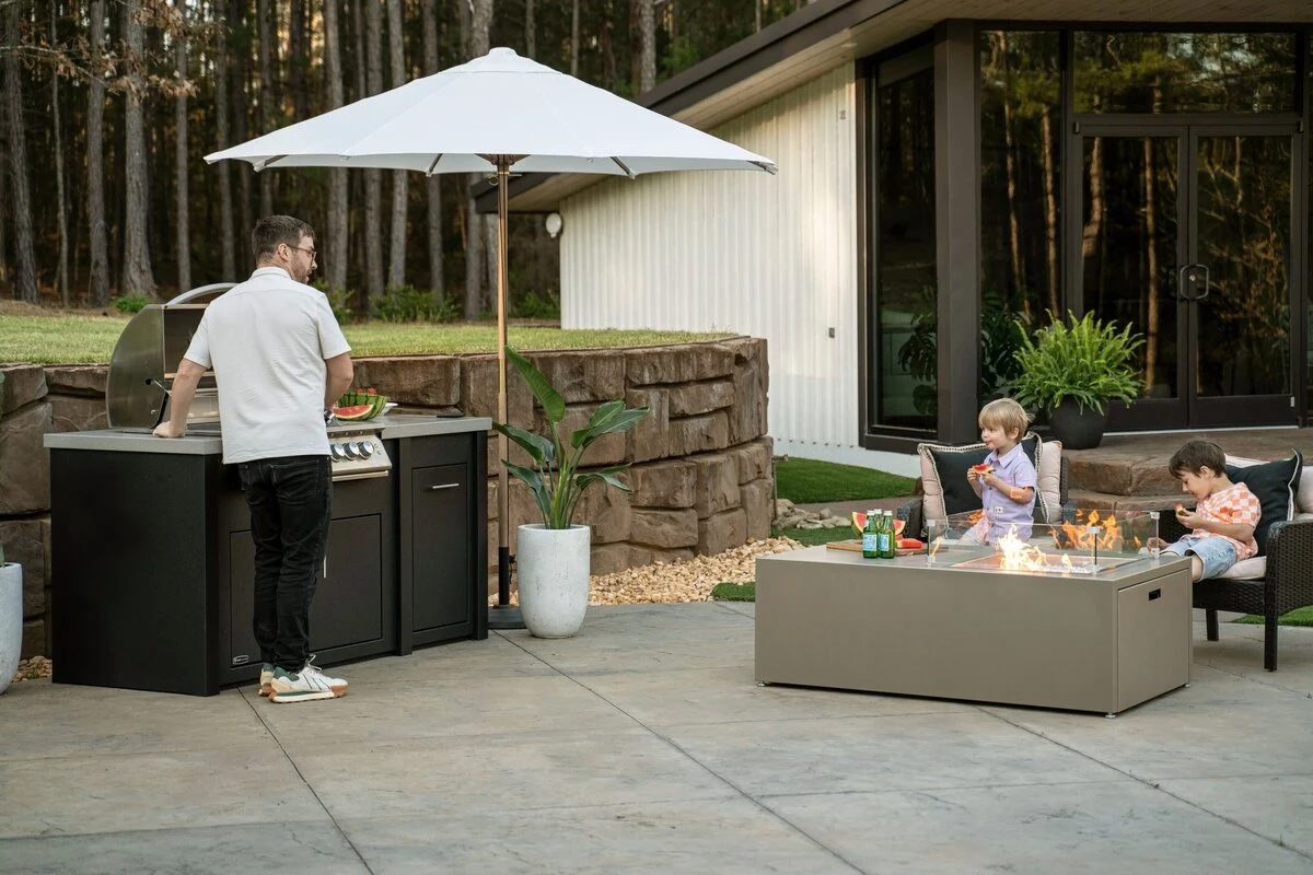 Custom outdoor kitchen with white cabinetry, stainless steel grill, and pergola on a warm patio. Shop near Rathdrum and Spokane.