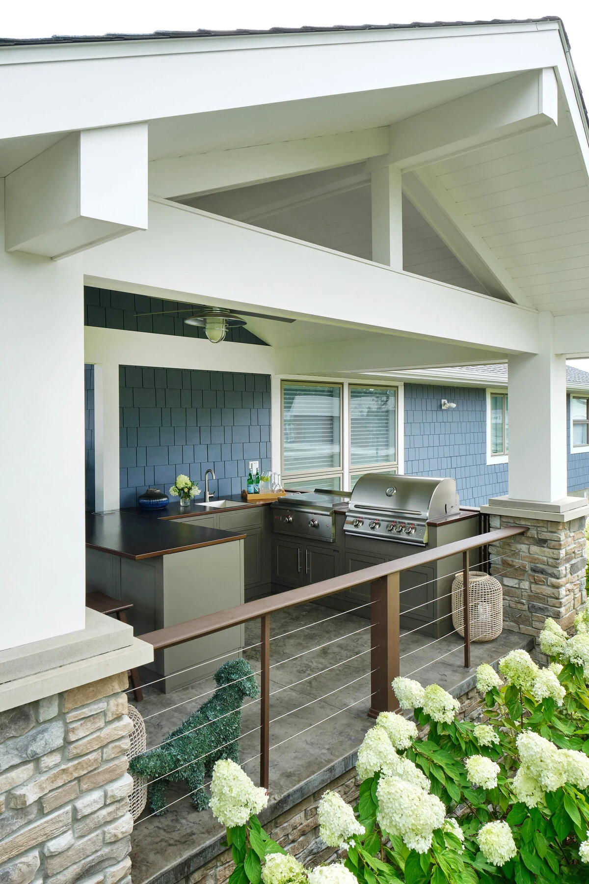 Custom outdoor kitchen with white cabinetry and stainless steel appliances on a bright contemporary patio. Available near Sandpoint and North Idaho.