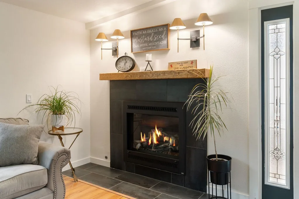 Gas fireplace with a black surround and wood mantel