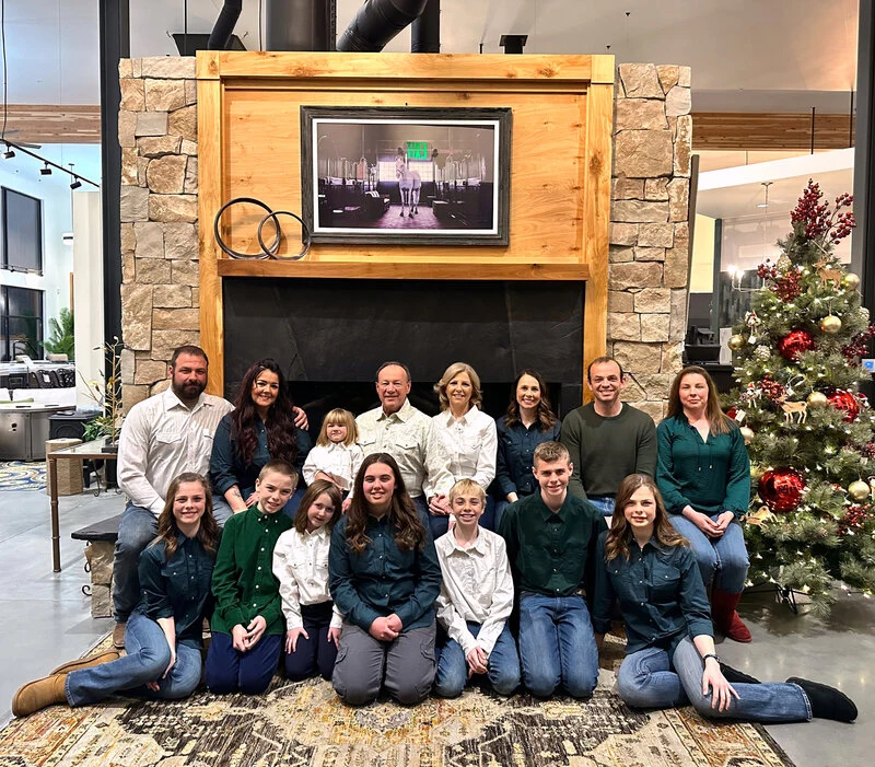 Quality Stoves & Spas owner family sitting in front of a fireplace in the showroom.