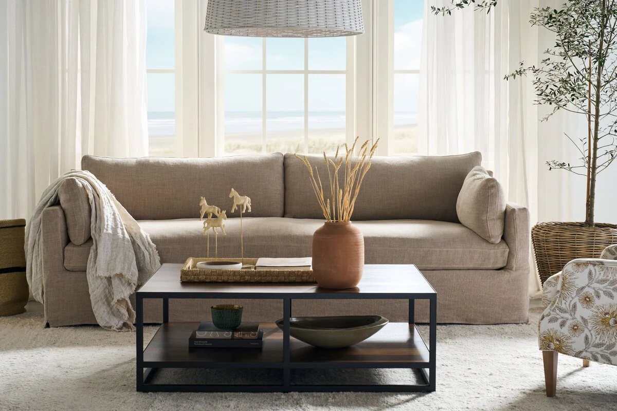 Linen sofa with a knit throw behind a dark wood coffee table