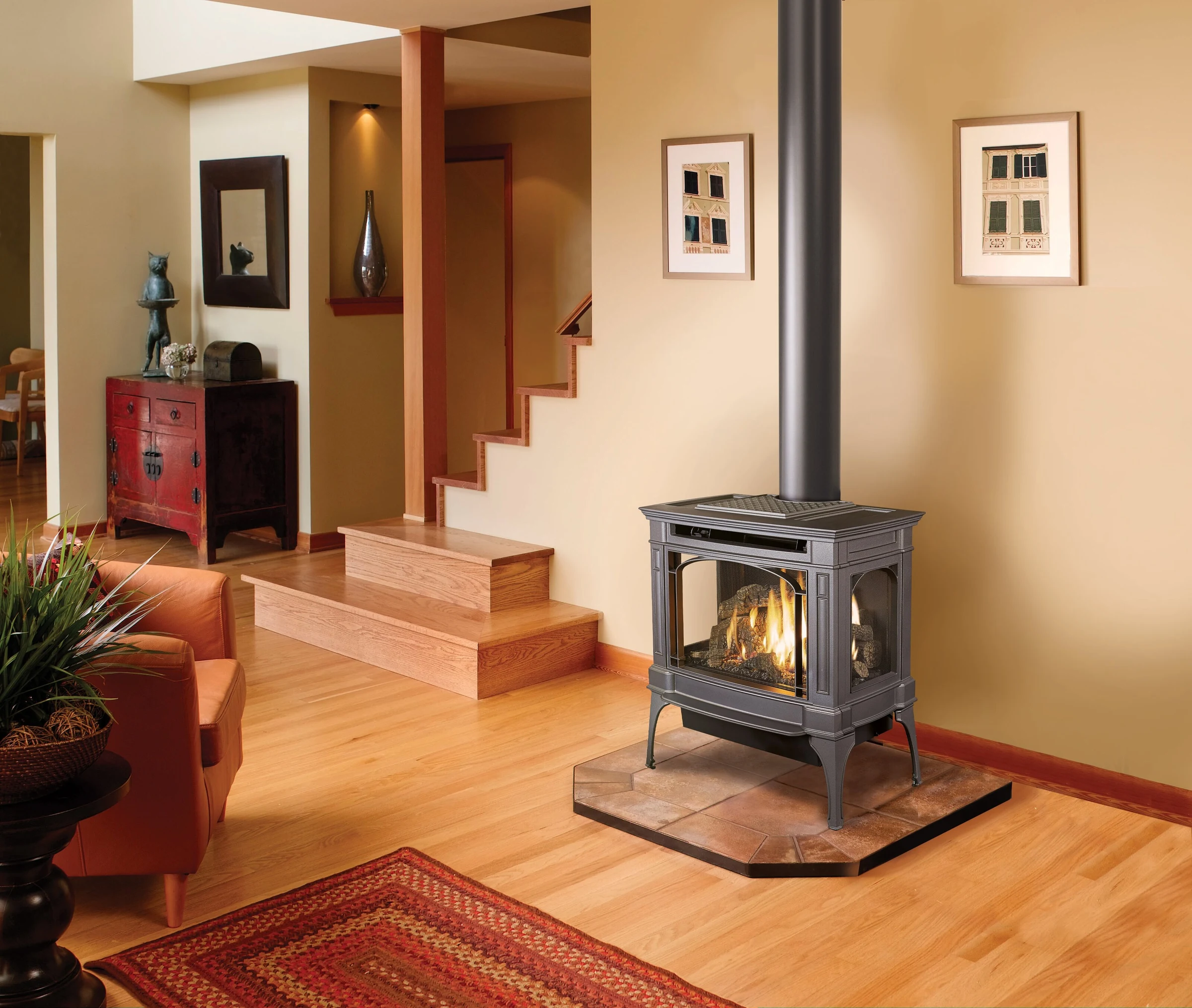 A Lopi Berkshire Bay Window gas stove positioned in a warm, traditionally styled room with hardwood floors and a staircase.