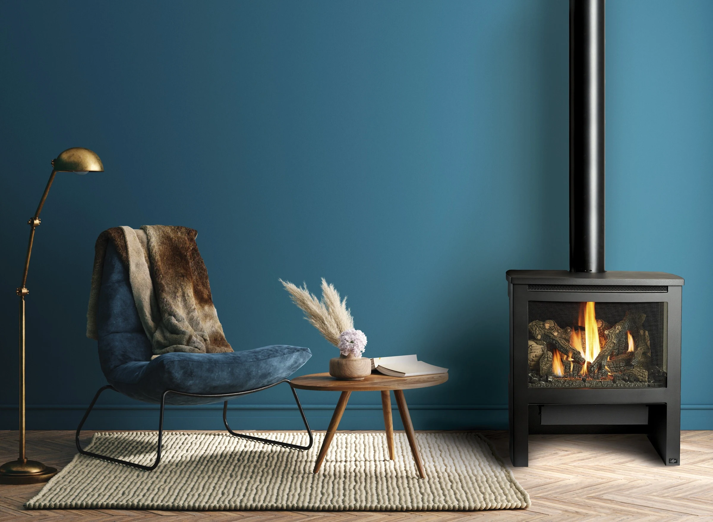 Lopi Cypress Bay Window Gas Stove against a teal accent wall with a wood coffee table and a chair with a throw blanket nearby.