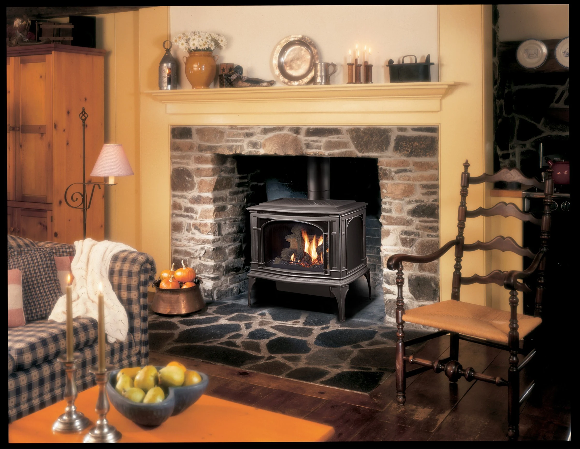 Lopi Greenfield Millivolt Gas Stove in a traditional living room with a stone fireplace surround and warm wood flooring.
