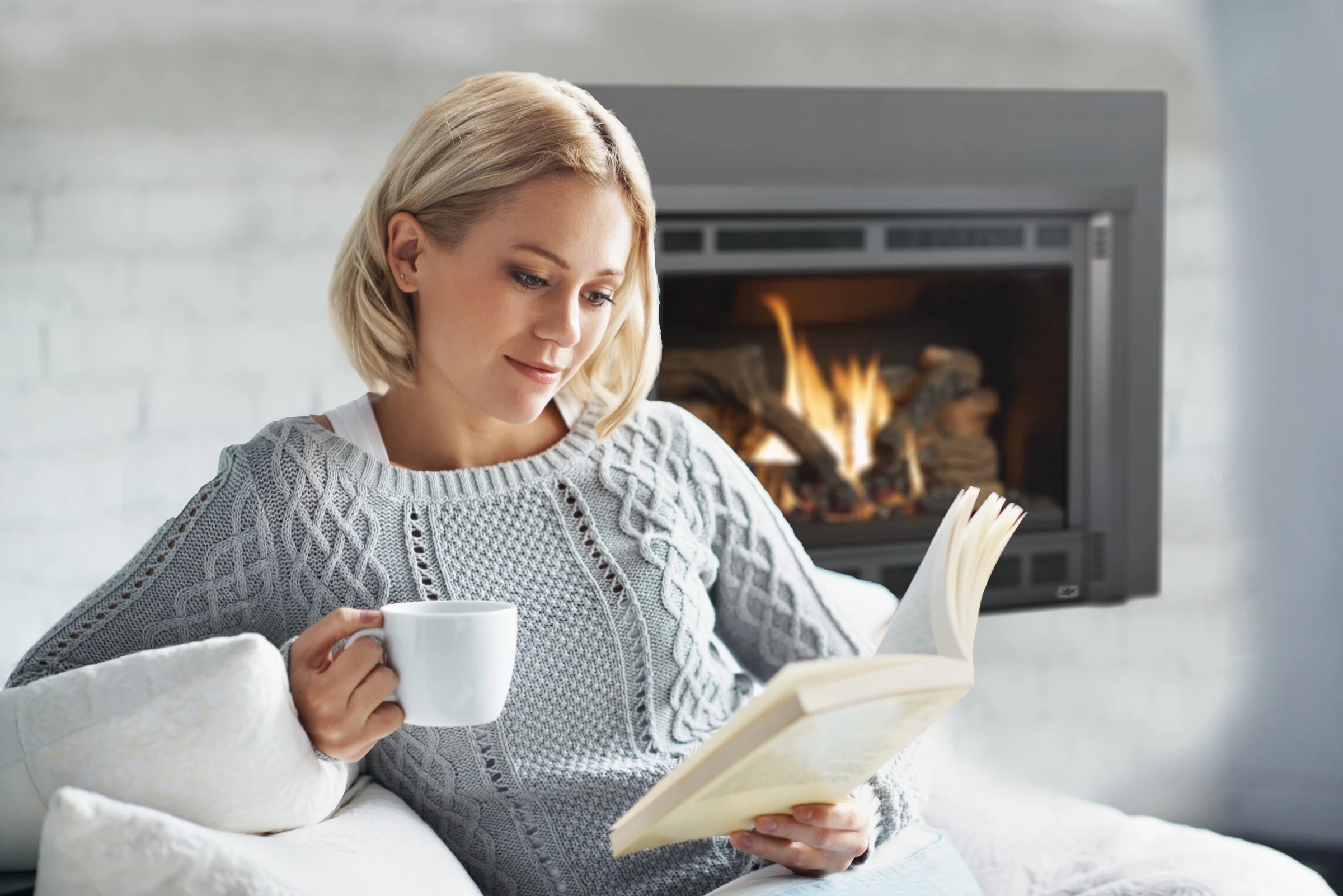 Woman reading by a Lopi Radiant Plus large gas insert fireplace.