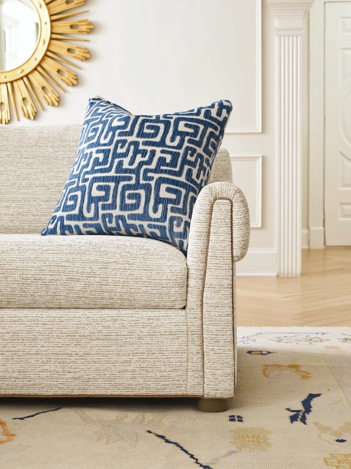 Cream upholstered chair with a navy geometric accent pillow