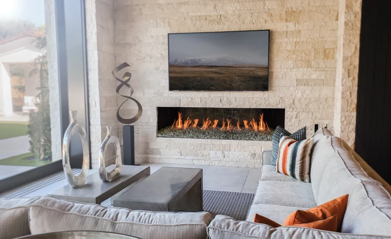 A linear gas fireplace set flush into a light gray wall in a modern living room with neutral furnishings.