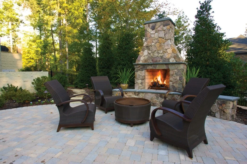 A linear gas fireplace set into a stone surround in a contemporary living room with neutral furnishings.