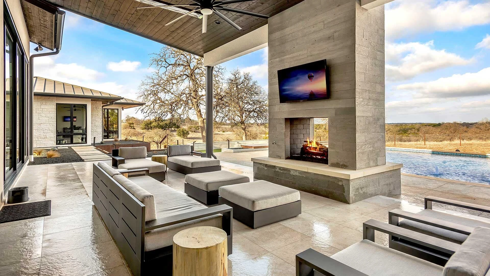 A linear gas fireplace set into a light stone surround in a contemporary open-concept living space with neutral furnishings.