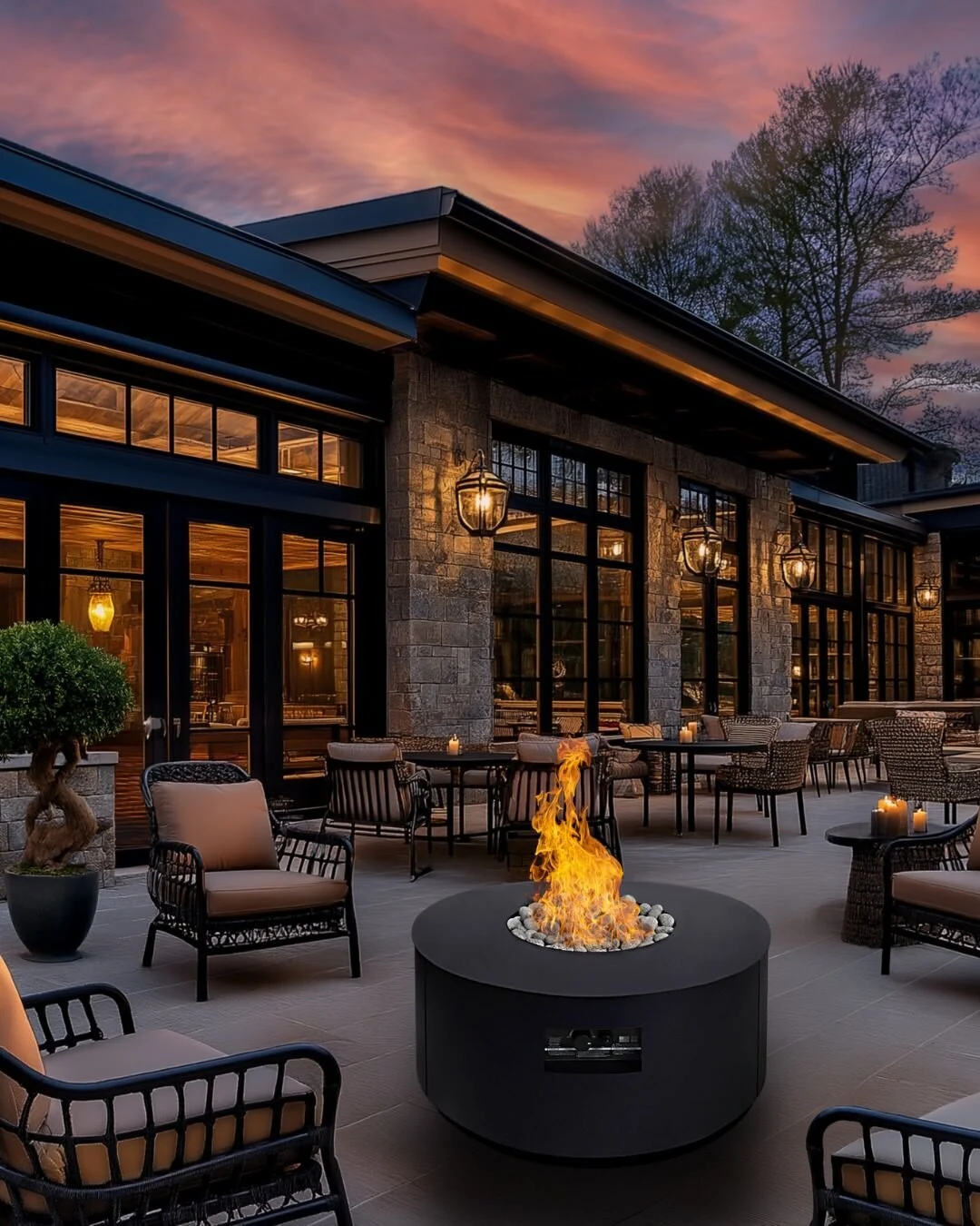 A rectangular fire table with an active flame on a modern outdoor patio with floor-to-ceiling windows and mixed seating.