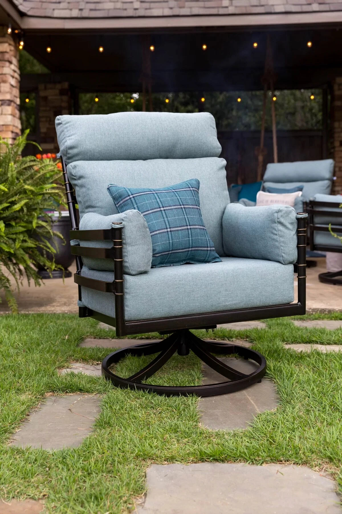 Blue cushioned swivel patio chair in a landscaped backyard
