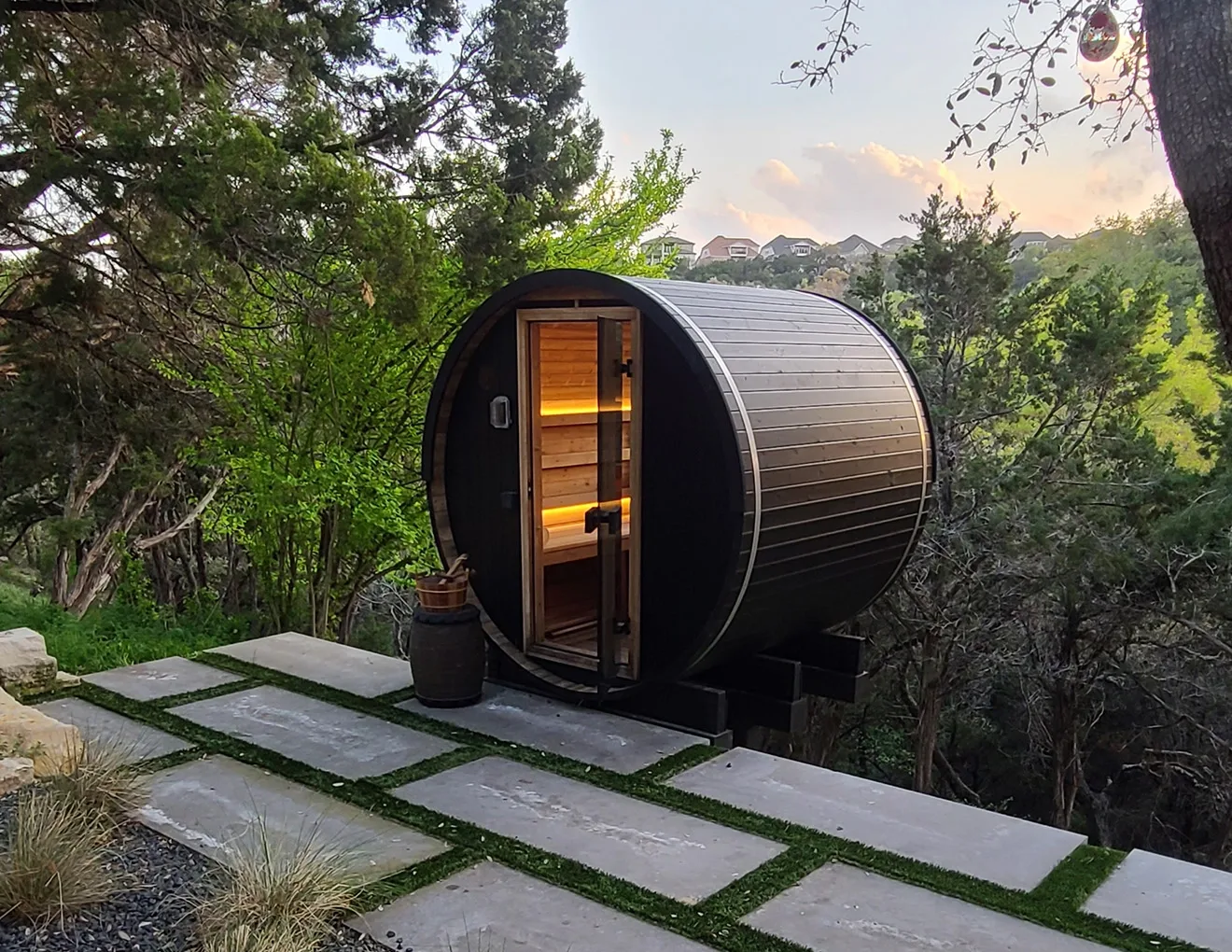 Thermory Ignite Barrel Sauna on a backyard paver patio at dusk
