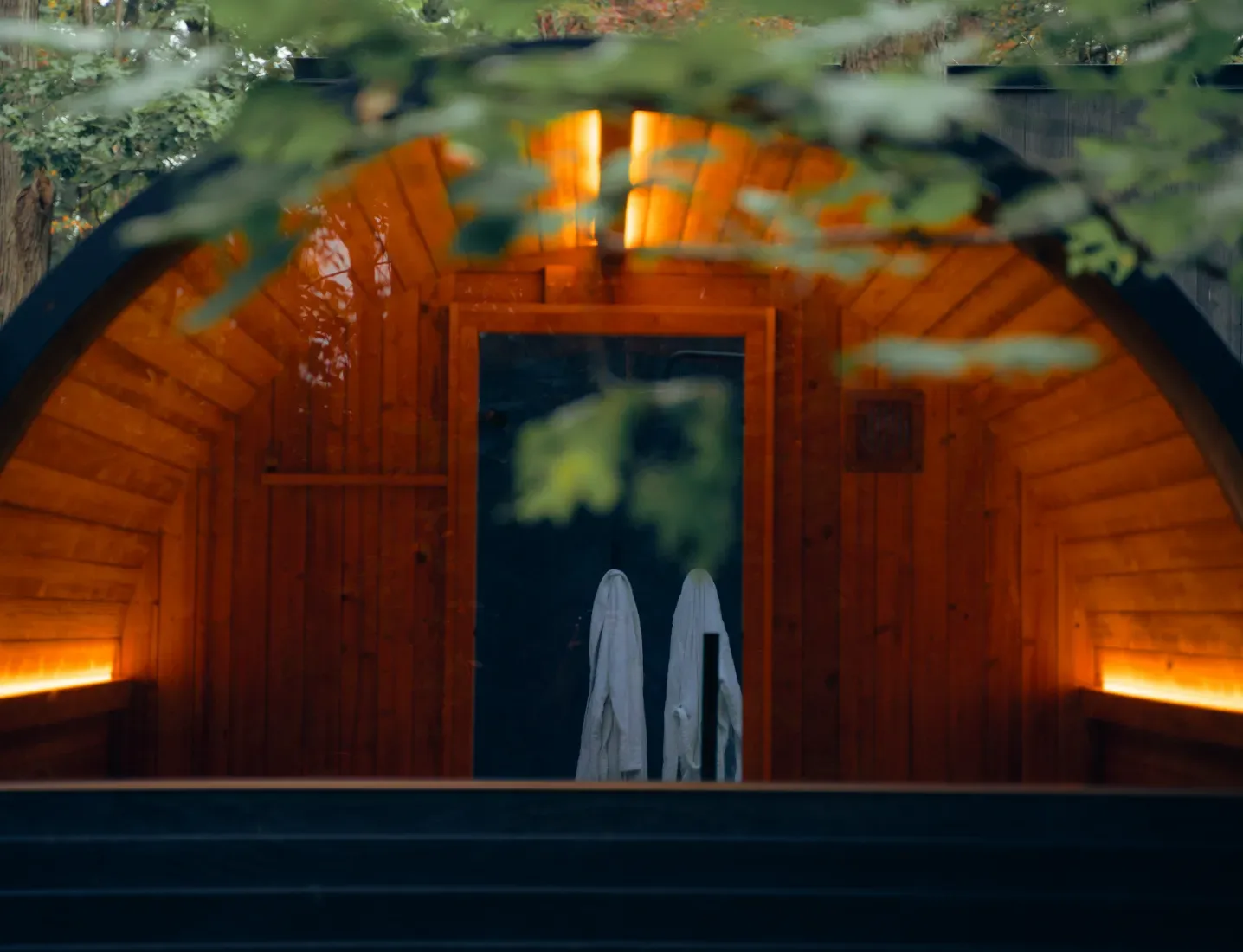 Thermory Ignite Barrel Sauna glowing at night with the door open
