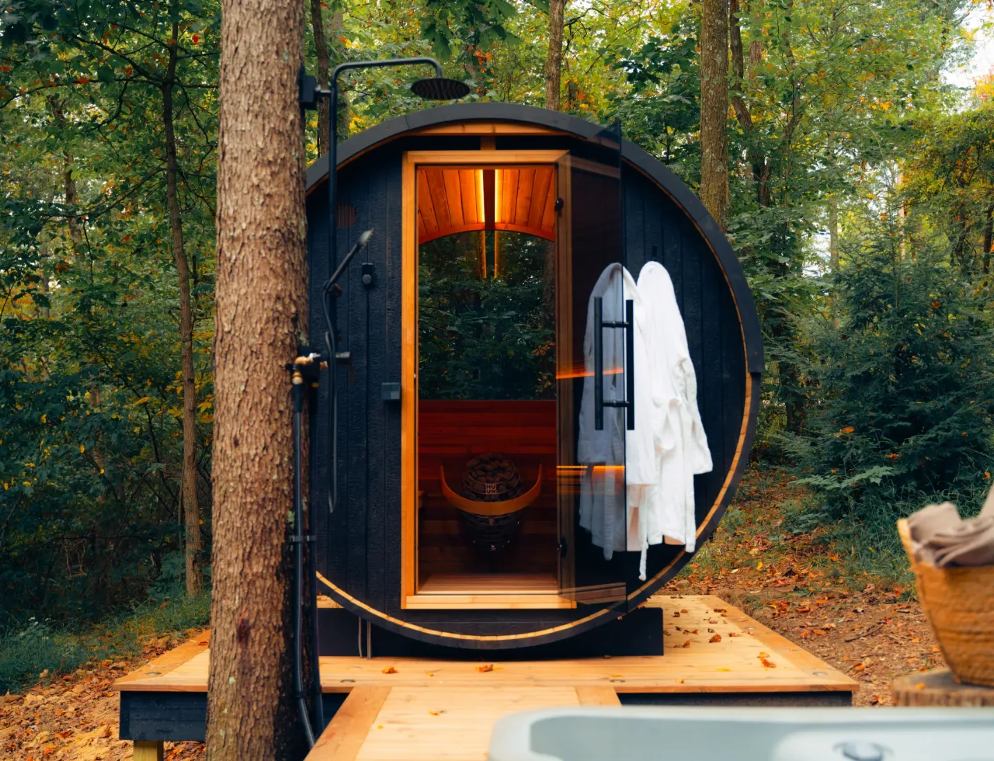 Thermory Ignite Barrel Sauna on a forest deck beside a hot tub