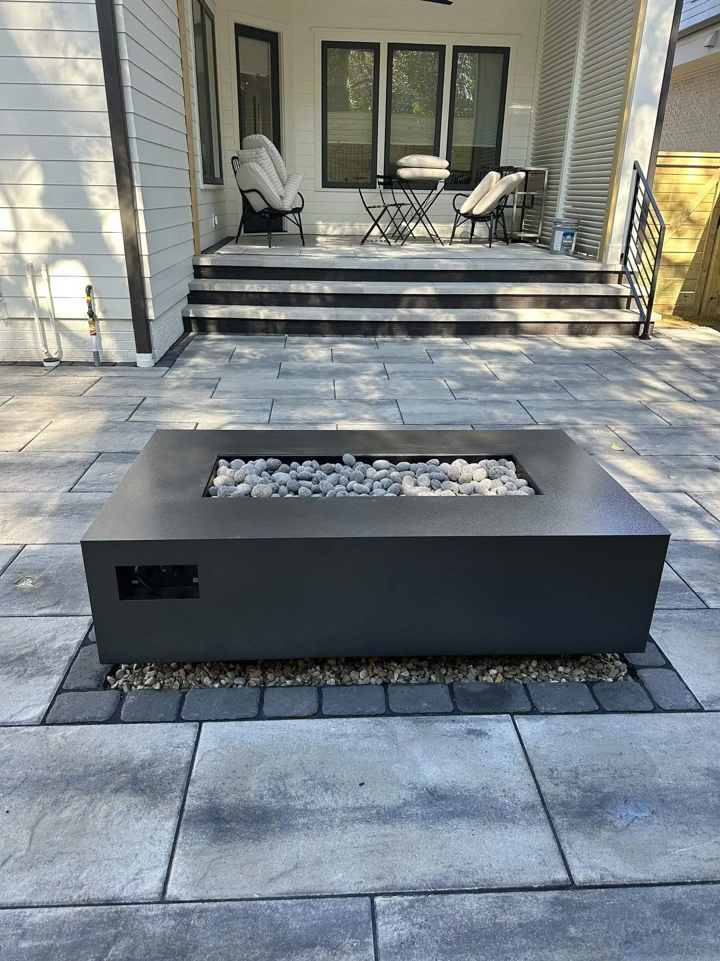 Warming Trends AON rectangle fire table in Black with lava rock media on a paver patio