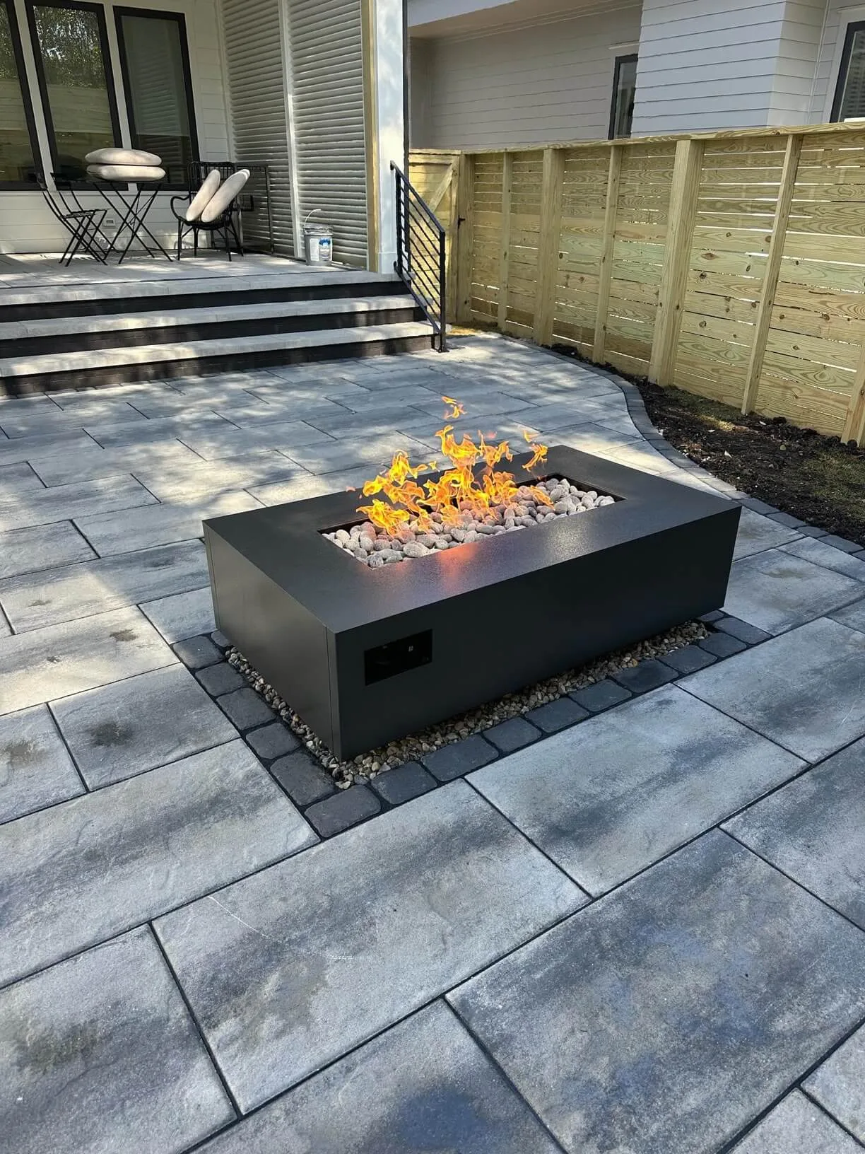 Warming Trends AON rectangle fire table in Black burning on a paver patio
