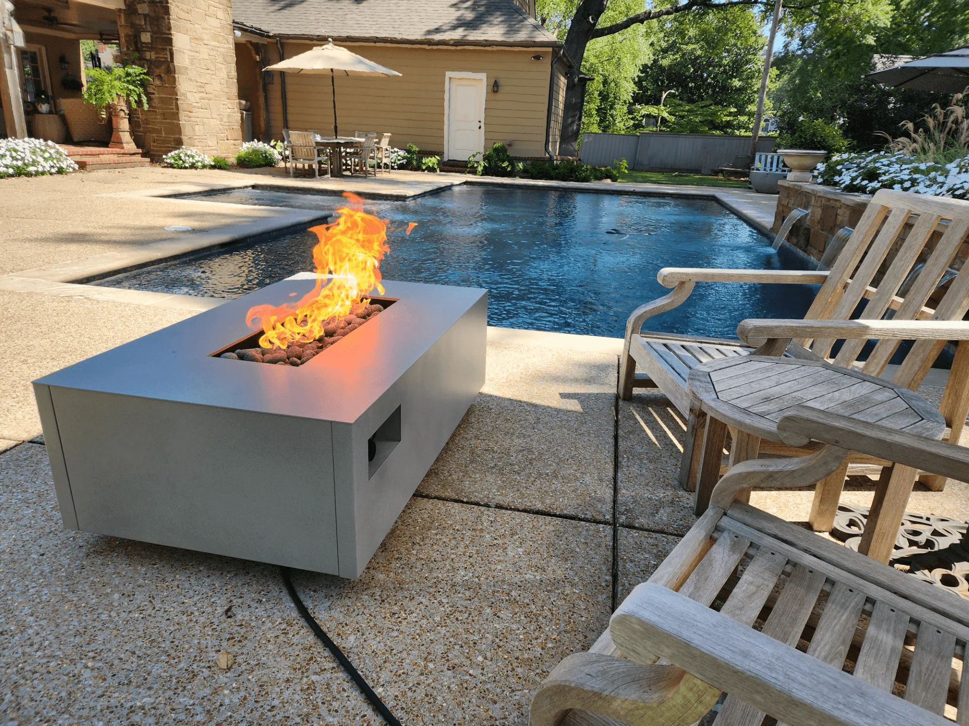 Warming Trends AON square fire table in Sand Pebble on a poolside patio