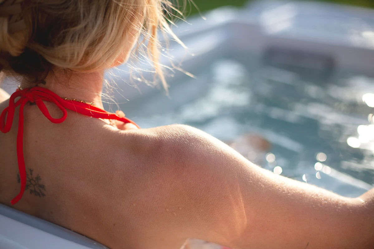 Woman soaking in a Wellis Iceland cold plunge tub in the sunshine