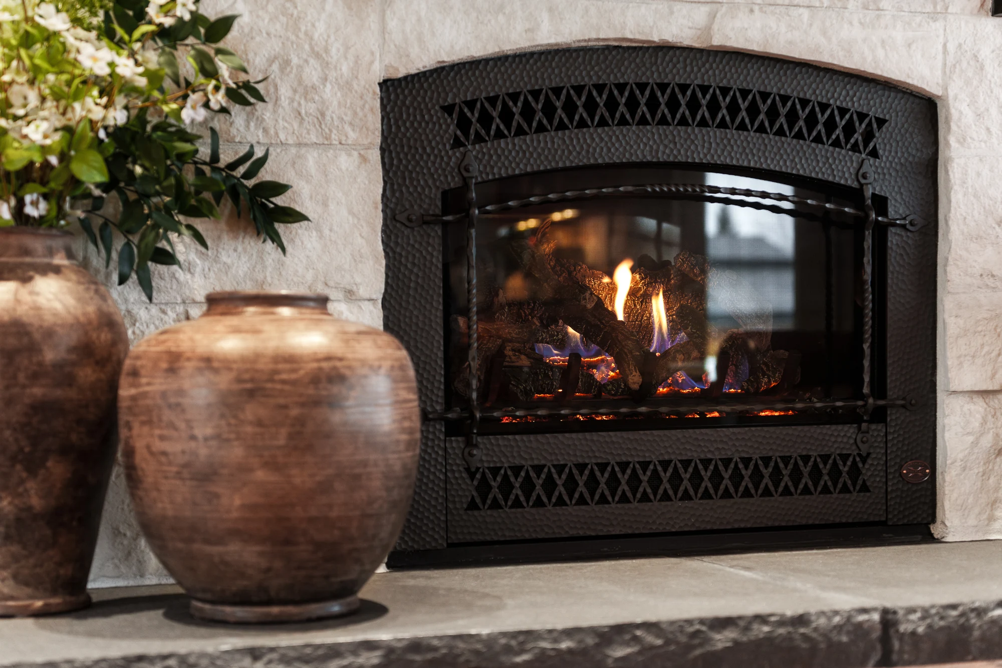 Gas fireplace with a hammered steel surround burning on display in the Quality Stoves and Spas showroom near Spokane.