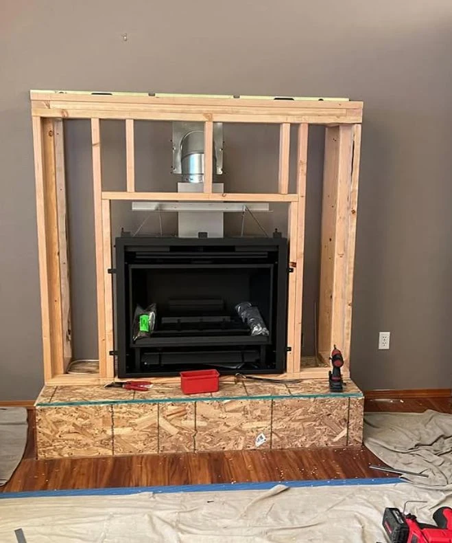 Wood framing and firebox during a custom fireplace installation with venting