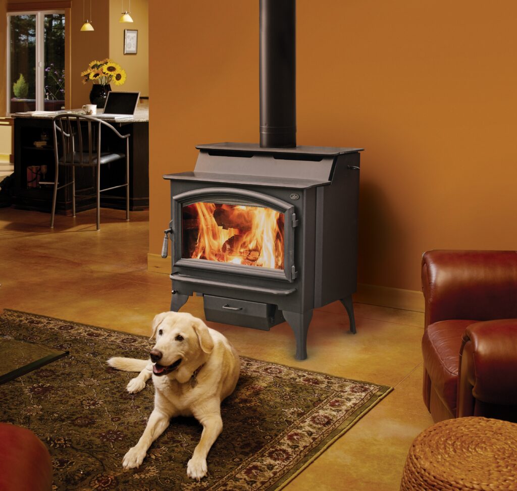 Yellow Labrador lying on a rug in front of a wood-burning stove.
